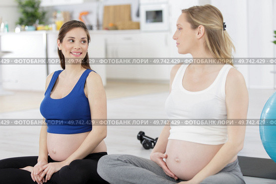 young pregnant women doing relaxation exercise on exercising mat. Стоковое фото, агентство Ingram Publishing / Фотобанк Лори
