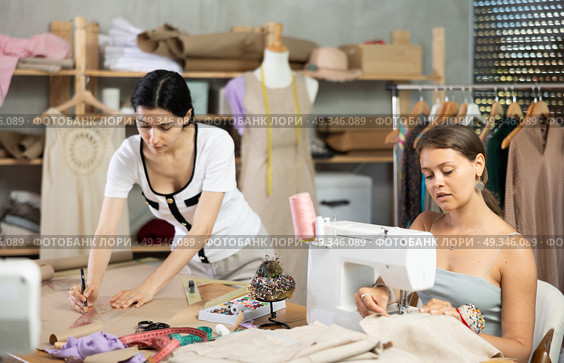 Young seamstresses stitching and drafting paper patterns in workshop. Стоковое фото, фотограф Яков Филимонов / Фотобанк Лори