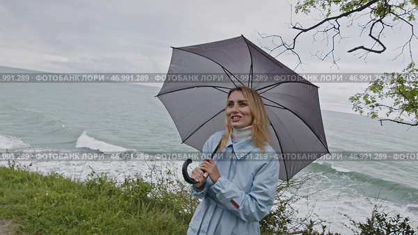 Young smiling woman with eyes full of love spinning grey umbrella. Стоковое фото, фотограф David Kashakhi / Фотобанк Лори
