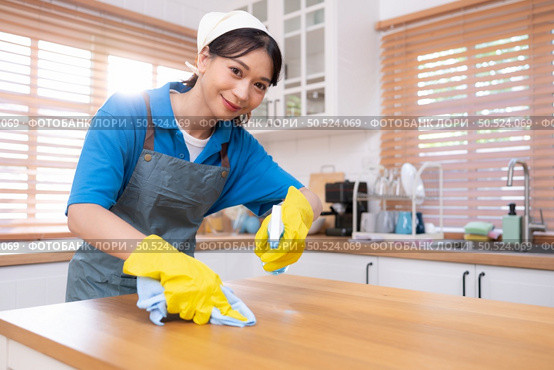 Young woman cleaning the table in the kitchen. Housekeeping and housekeeping concept. Стоковое фото, агентство Ingram Publishing / Фотобанк Лори