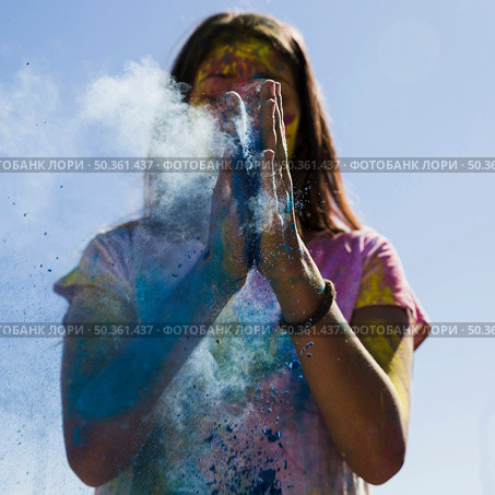 young woman dusting blue holi color with hands. Стоковое фото, агентство Ingram Publishing / Фотобанк Лори