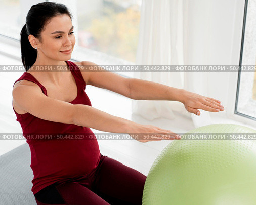 young woman exercising with fitness ball while being pregnant. Стоковое фото, агентство Ingram Publishing / Фотобанк Лори