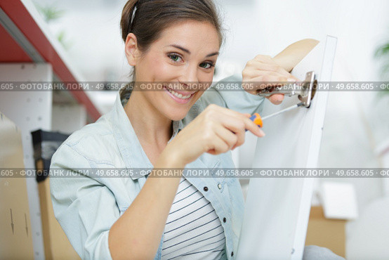 young woman is assembling a cupboard at home. Стоковое фото, агентство Ingram Publishing / Фотобанк Лори