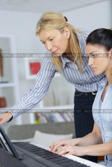 young woman learning play piano with teacher. Стоковое фото, агентство Ingram Publishing / Фотобанк Лори