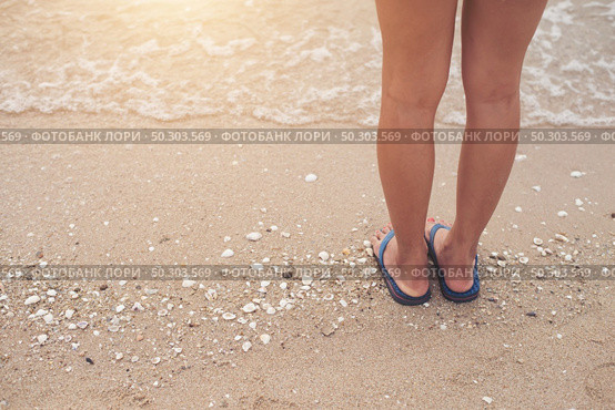 Young woman legs in flipflop sandals on sea beach. Стоковое фото, агентство Ingram Publishing / Фотобанк Лори