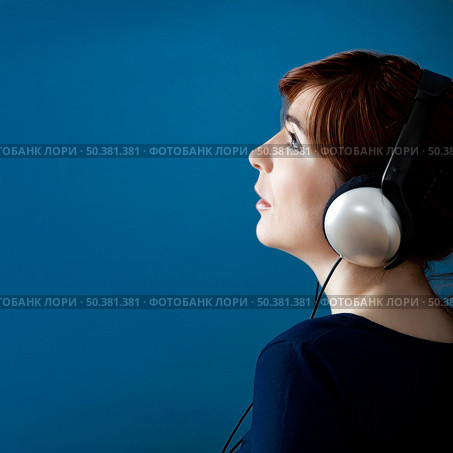 Young woman listen music with headphones over a blue wall. Стоковое фото, агентство Ingram Publishing / Фотобанк Лори