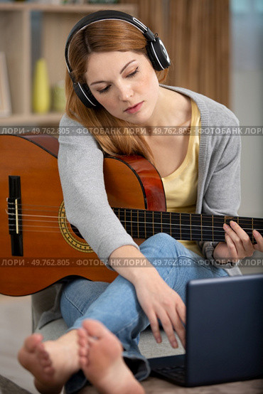 young woman playing records on guitar supported by laptop. Стоковое фото, агентство Ingram Publishing / Фотобанк Лори