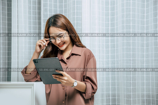Young woman wearing glasses using technology of digital pen on tablet to working from home during self-isolation and quarantine covid-19 coronavirus outbreak. Стоковое фото, агентство Ingram Publishing / Фотобанк Лори