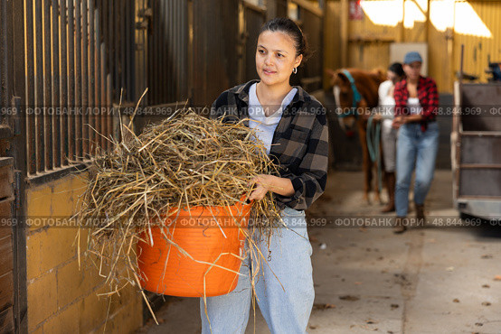 Young woman with bucket of hay in stables. Стоковое фото, фотограф Яков Филимонов / Фотобанк Лори