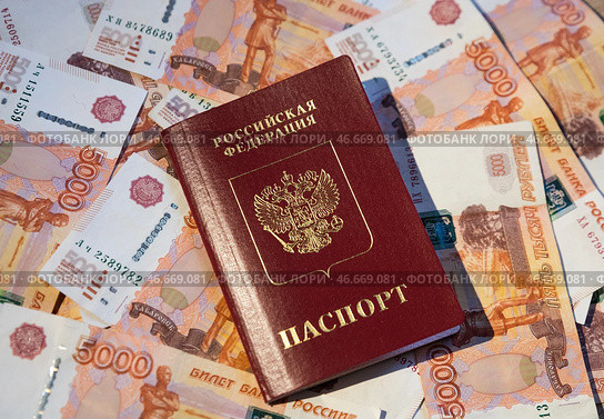 Заграничный паспорт гражданина Российской Федерации на фоне банкнот номиналом 5000 российских рублей. Стоковое фото, фотограф Александр Манзюк / ТАСС / Фотобанк Лори