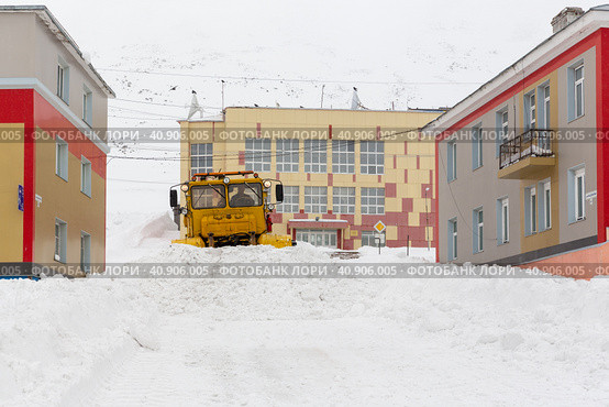 Заснеженная улица в северном городе в Арктике. Большие сугробы. Уборка снега с улиц после снегопада. Провидения, Чукотка, Крайний Север России. Редакционное фото, фотограф Андрей Степанов / Фотобанк Лори