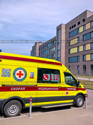 Жёлтый автомобиль скорой помощи - реанимобиль . Современное медицинское учреждение смешанного типа для взрослых и детей на 670 посещений в смену с пристроенной станцией " Скорой помощи " в жилом комплексе «Столичный» в мкр-не Саввино в Балашихе Московской области. Редакционное AI-изображение, AI-художник stargal / Фотобанк Лори