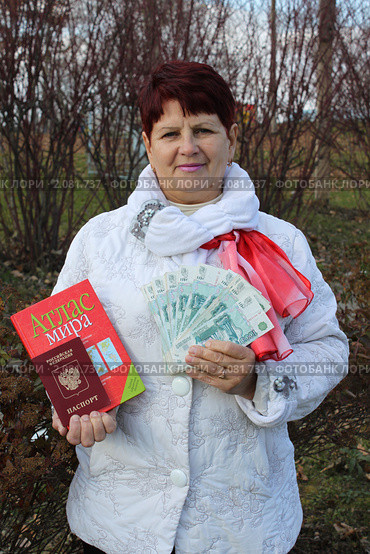 Женщина держит в руках атлас мира, заграничный паспорт и деньги. Стоковое фото, фотограф Ольга Линевская / Фотобанк Лори