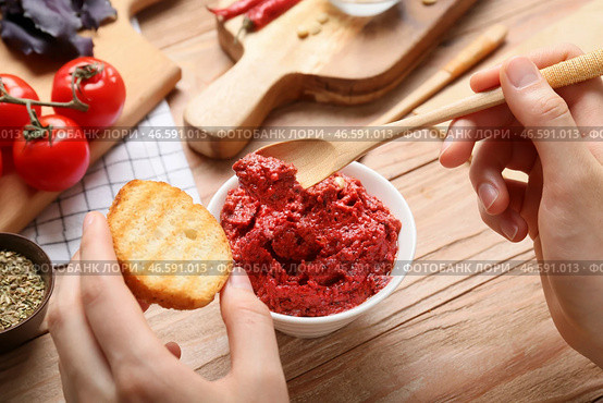 Женщина намазывает вкусный соус песто на тосты на деревянном фоне. Стоковое фото, фотограф Pixel_shot / Фотобанк Лори