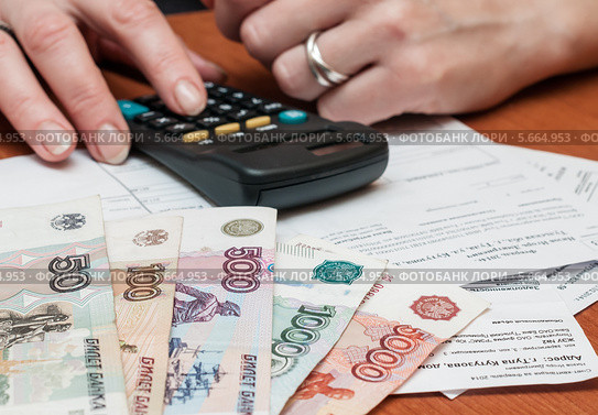 Женщина рассчитывает на калькуляторе расходы на коммунальные услуги (2014 год). Редакционное фото, фотограф Игорь Низов / Фотобанк Лори