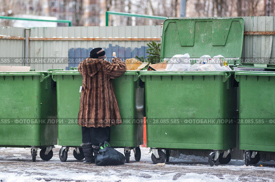 Женщина в шубе копается в мусорном контейнере (2017 год). Редакционное фото, фотограф Сайганов Александр / Фотобанк Лори