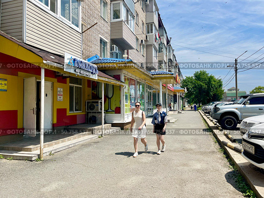 Женщины идут мимо дома номер 2 по улице Постышева в Находке. Приморский край. Редакционное фото, фотограф Овчинникова Ирина / Фотобанк Лори