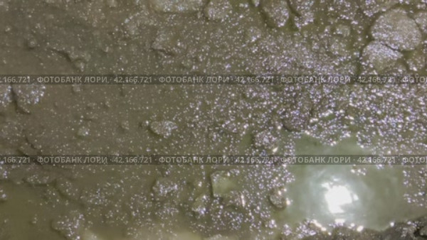 Зимняя лужа с мутной водой. Темно-серая поверхность воды в грязной луже покрыта кусочками битого льда. Уличный фонарь отражается в свободном ото льда пространстве. Капли дождя падают в воду. Стоковое видео, видеограф Andrew_Swarga / Фотобанк Лори