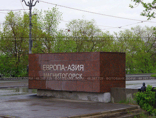 Знак "Европа-Азия Магнитогорск" у западного конца Центрального перехода. Идет дождь. Редакционное фото, фотограф Алексей Иванов / Фотобанк Лори