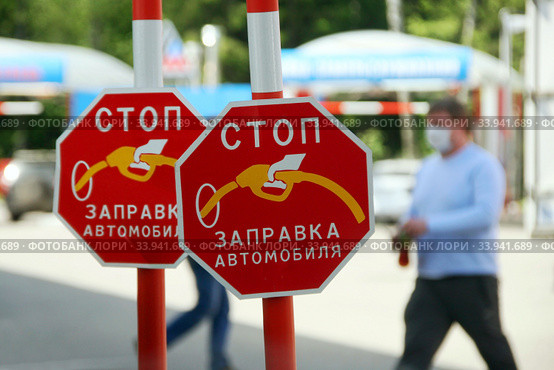 Знак "Стоп. Заправка автомобиля" на АЗС. Водитель в медицинской маске на заднем фоне.  Масочный режим. Пандемия коронавируса COVID-19 в России, 2020 год. Стоковое фото, фотограф Щеголева Ольга / Фотобанк Лори