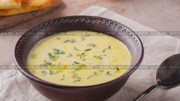 Zoom in video of cheese soup with yellow sweet pepper and thyme on a beige background. Vegetarian food. Стоковое видео, видеограф Мария Зубарева / Фотобанк Лори